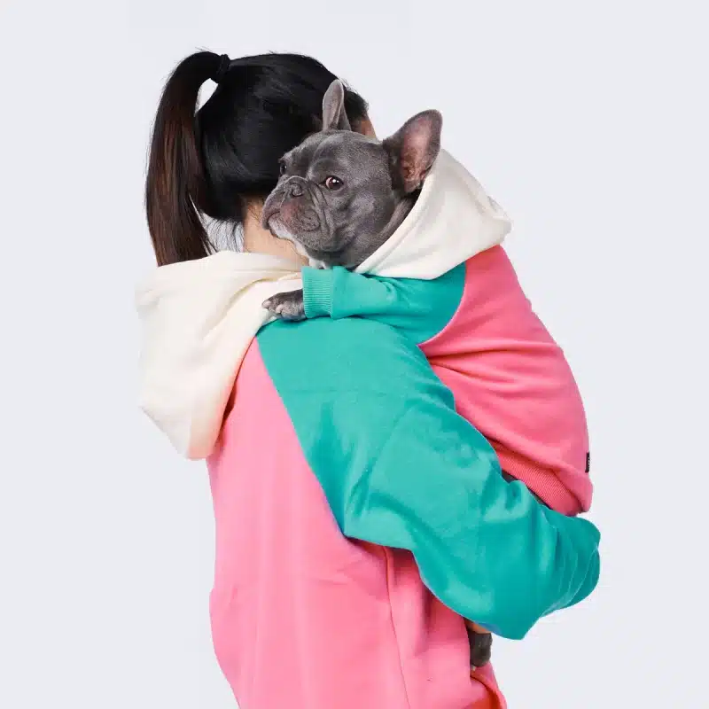 una mujer sosteniendo un perro en hoodie