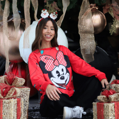 una mujer sentada frente a regalos bajo un árbol de navidad