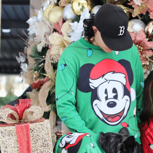 un hombre y una mujer en pijama de mickey mouse junto a un árbol de navidad