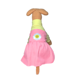 un perro de peluche con un vestido rosa y sonriendo